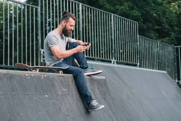 Skateboarding hombre descanso relajación rampa smartphone — Foto de Stock
