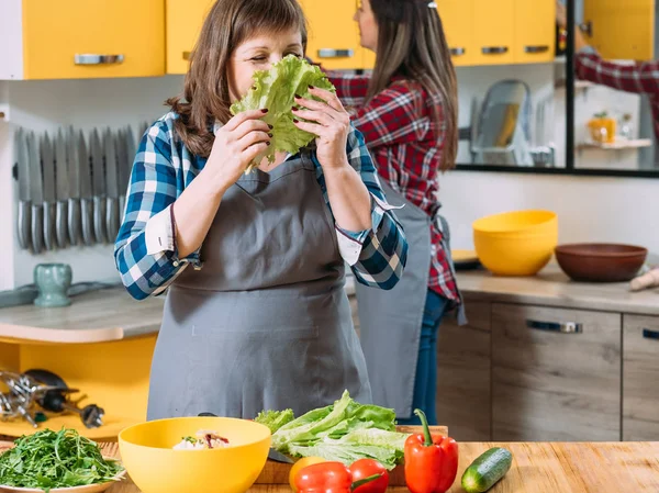 Två kvinnor kök matlagning mamma luktar sallad — Stockfoto