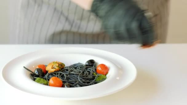 Food stylist arranging squid ink italian pasta — Stock Video