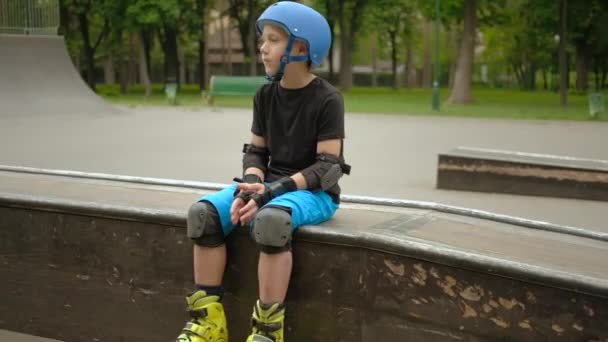 Criança esporte hobby rolo menino sentado esperando skate — Vídeo de Stock