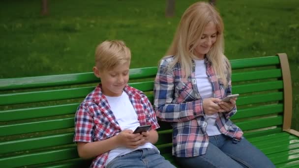 Mensajes de texto comunicación mamá hijo sentado banco teléfono — Vídeos de Stock