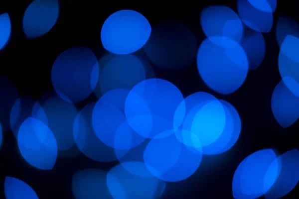 Mavi bokeh ışıkları siyah arkaplanı aydınlatır — Stok fotoğraf