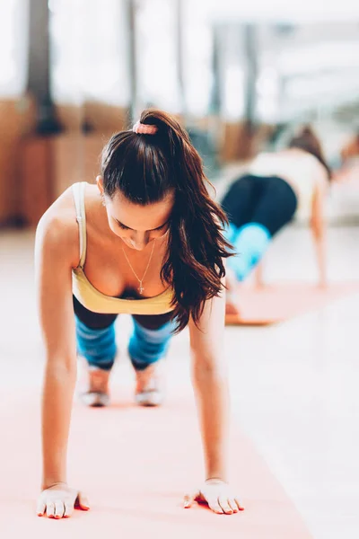 Домашний фитнес брюнетка леди отжимания циновки йоги — стоковое фото