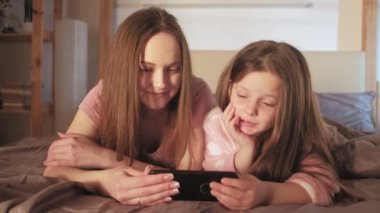 Anne kızı boş vakitlerinde video telefon yatağı izliyor.