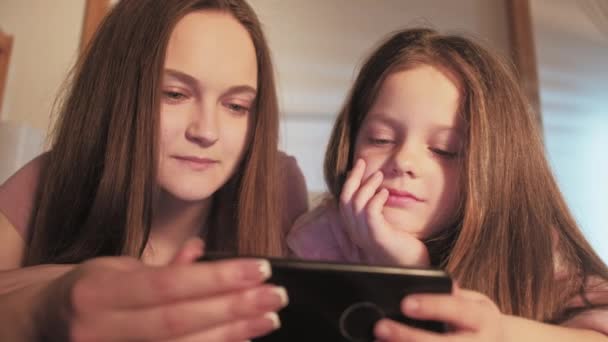 Hermanas ocio casa descanso niñas viendo el teléfono — Vídeo de stock