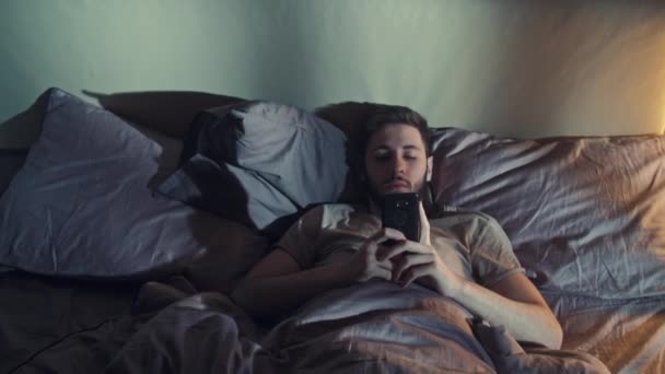 Éjszaka online digitális méregtelenítő unatkozik férfi telefon ágy — Stock videók