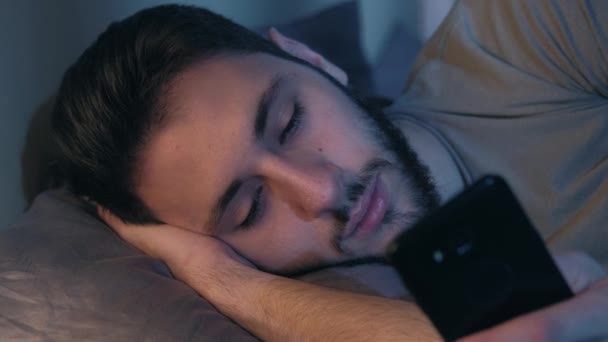 Bezesná noc znuděný muž pomocí telefonu ležící postel — Stock video