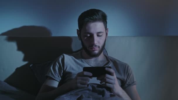 Bezsenna noc zmęczony człowiek oglądanie wideo łóżko telefon — Wideo stockowe