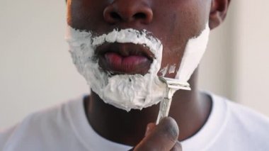 Berber dükkanı işleten adam. Zenci adam yüzünü tıraş ediyor.