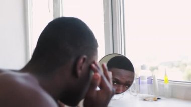 Yaşlanma önleyici tedavi gören adam cildine bakıyor.