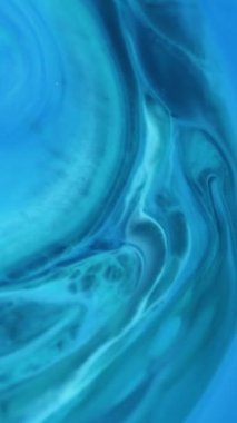 Dikey video. Mürekkep parçacıkları. Akrilik sıvı. Su mermeri emaye dokusundaki bulanık mavi cyan rengi kimyasal madde soyut arkaplanda hareket ediyor.