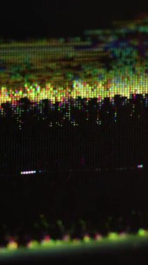 Dikey video. Renk bozulması. Arıza dokusu. Odaklanamayan sarı yeşil titreşimli objeler koyu siyah kaba arkaplan üzerinde ekran pikseli dijital.