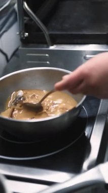 Dikey video. Karışık çorba. Deniz mahsulleri pişiriyorum. Şef elektrikli sobada kahverengi yemek tenceresi hazırlıyor. Baharatlı Asya yemeği gurmesi..