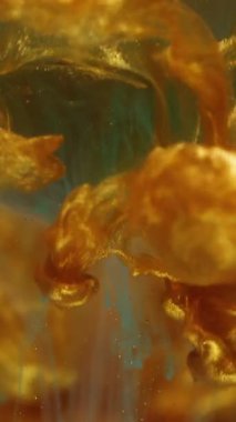 Dikey video. Parçacıklar boyar. Sıçrama küresi. Soyut sanat arka planında odaksız altın sarısı mavi parlak su dokusu.