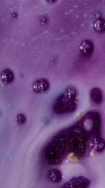 Dikey video. Parıltı karışımı. Akrilik sıvı. Soyut sanat arka planına yayılan kimyasal suda parlayan mor altın rengi..