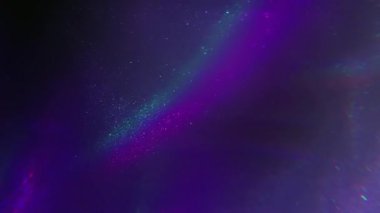 Flüoresan ışını. Parlak akış. Odaklanmamış mor mavi renk parıltısı soyut koyu siyah ışık arka planında ışıldayan neon gökkuşağı parçacıkları.