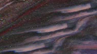 Parıldayan sıvı. Sıvı doku. Odaklanmamış pembe kırmızı renk soyut yaratıcı sanat arka planında yüzen koyu siyah mürekkep parçacıkları sıçratır.