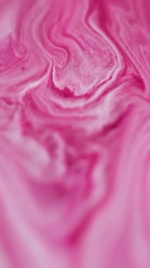 Dikey video. Dalgalı boya. Parlak sıvı. Soyut arkaplanda yayılan pembemsi beyaz renkli mermer sıvı akrilik parçacıklar..