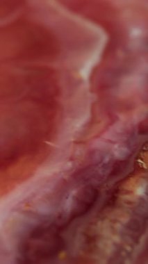 Dikey video. Mürekkep döküldü. Parlak lekeler. Soyut arkaplan üzerinde yüzen suda çözünmüş kırmızı sarı renkli mermer emaye desenli boya akışı.