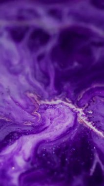 Dikey video. Köpüklü sıvı. Mermer sanat. Bulanık mor beyaz renkte, su parçacıklarında parıldayan boya soyut bokeh ışık arka planına dökülüyor..