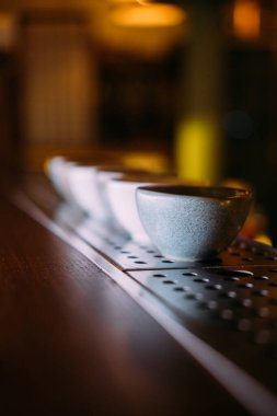 Asya barı. Sake bardağı. Geleneksel oryantal alkollü içecek seti. Bar tezgahında boş yeri olan kil bulaşık takımı sırası.