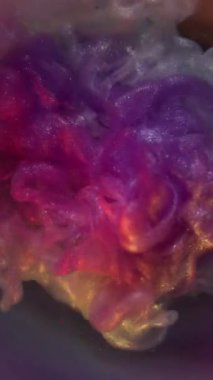 Dikey video. Yanardöner dalga. Duman sıçrıyor. Mor menekşe, gümüş sprey, mürekkep parlatıcı, patlama karışımı. Odaklanmamış arkaplan dairesi hafif üfleme rengi.