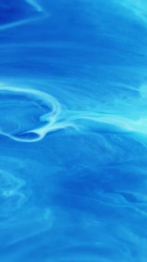 Dikey video. Boya parçacıkları. Parlak su. Odaklanmamış mavi beyaz pigment sıvı damlalar soyut sanat arka planına dökülen parlak doku.