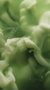 Dikey video. Dalga sisi. Sis mürekkebi. Kıvrımlı beyaz boya patlaması yeşil mermer su akışı. Renkli sanat sisi bulut patlaması sıvı arkaplan bulanıklığı.