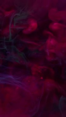 Dikey video. Metalik mürekkep. Parıltı akışı. Pembe parlak yeşil sıvı mistik buhar suyu karıştırıyor. Uçan renk düşüşü soyut arkaplan odaklı değil.