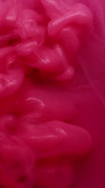 Dikey video. Işıldayan sıvı. Pigment akışı. Islak, soyut, bulanık arkaplanda pembe, parlak boya şişirme dalgası dökülmüş. Yumuşak sis rengi kıvrımlı su dumanı.
