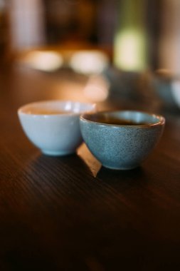 Sake bardağı. Alkollü içki servisi. Geleneksel Asya içeceği için bir çift boş kil kasesi. Bar masasında pirinç şarabı için seramik.