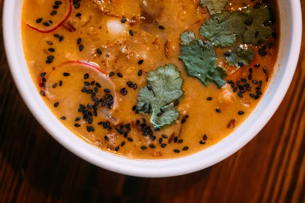 Susam çorbası. Sıcak yemek. Ahşap masada sebze sebzeleriyle servis edilen portakal suyu çorbası. Lezzetli aromalı turplu baharatlı yemek..