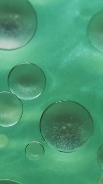 Dikey video. Kabarcık boyası. Arka planı bırak. Sudaki çözünmüş yeşil mürekkep. Soyut sanatın üzerine dökülen yağ yuvarlak sıvı emülsiyonu..