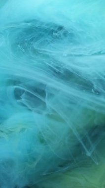 Dikey video. Sis sıvısı. Haze boyası. Yeşil mavi duman kıvrımlı ipekten sıvı akıyor. Suyu bulanıklaştıran hipnotik dalga yayılması soyut arkaplan karışımı.