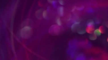 Bokeh çemberi. Bulanık mermi. Çok renkli mor ışıklı lens yanıp sönen desen parıltısı koyu soyut modern arka planda süzülüyor..