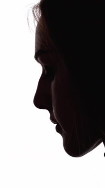 Dikey video. Üzgün surat. Kadın silueti. Hayal kırıklığı yalnızlık. Koyu renk karşıtlık profili, üzgün, depresif bir kadının beyaz boş alana izole edilmiş bakışları..