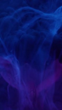 Dikey video. Su mürekkebi dumanı. Küre dokusu. Odaklanmamış mavi neon rengi sıvı duman soyut sanat arka planında yüzen ıslak boya..