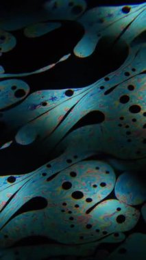 Dikey video. Gökkuşağı sıvısı. Sabun köpüğü. Sanat petrol zemininde neon pigment mürekkep karışımı. Soyut prizma bulanık ışık renk karışımı.