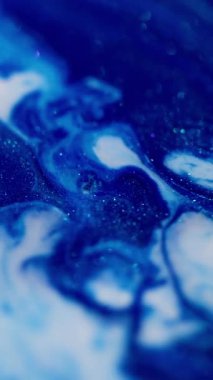 Dikey video. Damla soyut. Dalgalanma. Işıl ışıl arka planda yüzen sıvı köpük damlalarında mavi renkli mermer boya..