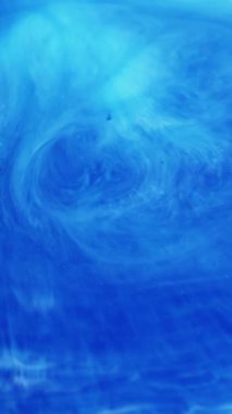 Dikey video. Arkaplanı boya. Renkli su. Bulanık mavi cyan parlak parçacıklar sanat soyutlamasına yayılan kimyasal emaye ıslak doku emülsiyonunu karıştırıyor.