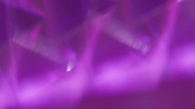 Kaleydoskop üçgenleri. Odaklanmamış parlaklık. Sarı yeşil, mor, parlak, parlak desenli mercek fişeği soyut, aydınlık arka planda hareket ediyor..