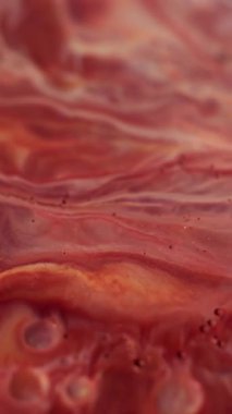 Dikey video. Kabarcık mürekkebi. Dalgalanma. Su sıvısında çözünmüş kırmızı beyaz mermer boya. Soyut arkaplana sıçramış..