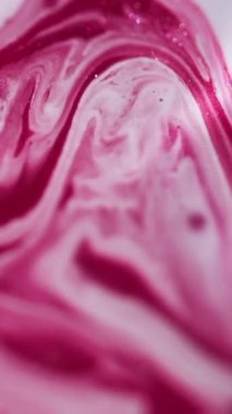 Dikey video. Arkaplanı boya. Renkli su. Soyut akrilik sanatta, kimyasal suda parlayan, çözünmüş pembe diş minesi dokusu..