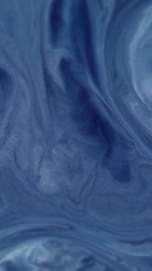 Dikey video. Mürekkep lekeleri. Karışım akışı. Soyut arkaplanda yüzen mavi renkli kimyasal su mermer parçacıkları diş minesi dokusu.