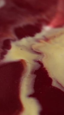 Dikey video. Mürekkep suyu. Mermer dokusu. Bulanık kırmızı renk, parlak sıvı kimyasal sıvı soyut akrilik arka plana yayılıyor..