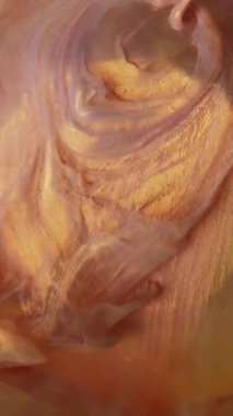 Dikey video. Parlatıcı dök. Işıldayan boya. Altın bej renkli parlak parçacıklar yuvarlak elmasa damlıyor. Soyut duman cilası bulanık sarı sanat arka planı.