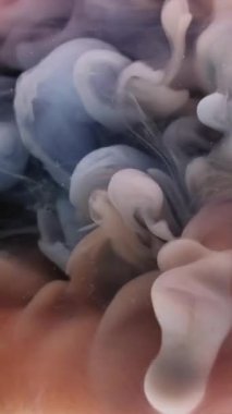 Dikey video. Dalga sisi. Sis mürekkebi. Kıvrımlı gri boya akışı şeftali rengi mermer su. Renkli sanat sisi patlama sıvısı arka planı bulanık.