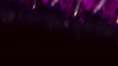 Bulanık ışık dokusu. Işık huzmesi. Odaklanmamış mor neon renkli floresan optik lens koyu siyah görsel arka planda daireler çiziyor..