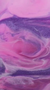 Dikey video. Boya sıçraması. Mermer dokusu. Soyut sanat arka planına yayılan sıvı yağ karışımında çözünmüş pembe renk mürekkebi..