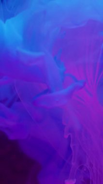 Dikey video. Sıvı dumanı. Yuvarlak doku. Odaklanmamış mavi neon rengi su boyası soyut yaratıcı arka planda süzülen duman damlası.